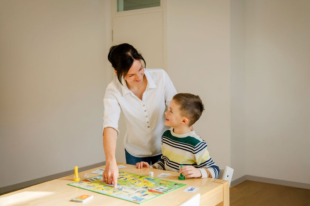 Logopädin spielt mit einem Kind ein Brettspiel während der Therapie